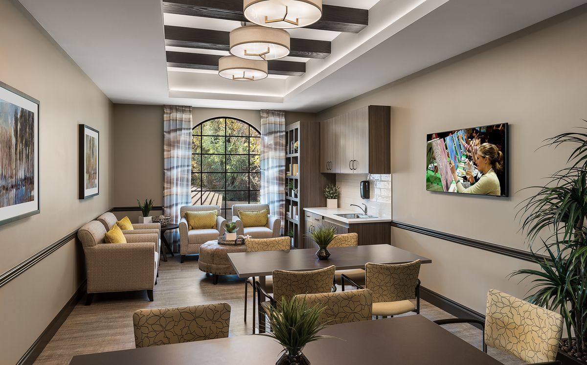 A modern living room with a kitchen area, featuring elegant furniture and lighting.