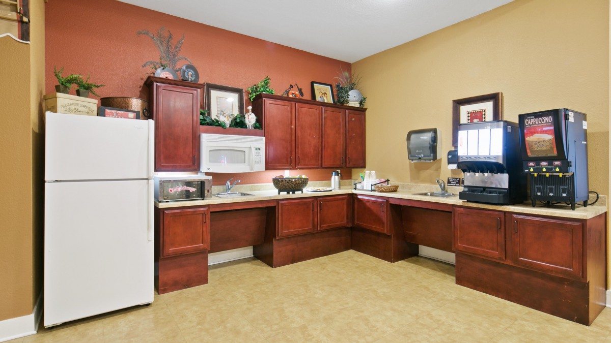 A modern kitchen with wooden cabinets, a white refrigerator, and a microwave.
