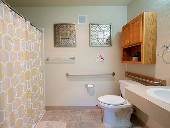 A clean and organized bathroom featuring a toilet, sink, shower curtain, and wall-mounted cabinet.