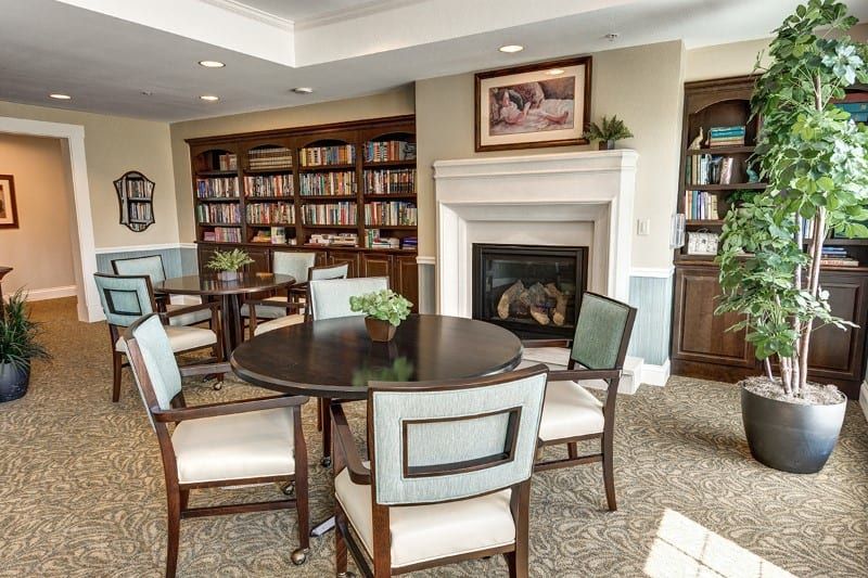 Cozy library interior with bookshelves, a fireplace, and seating area.