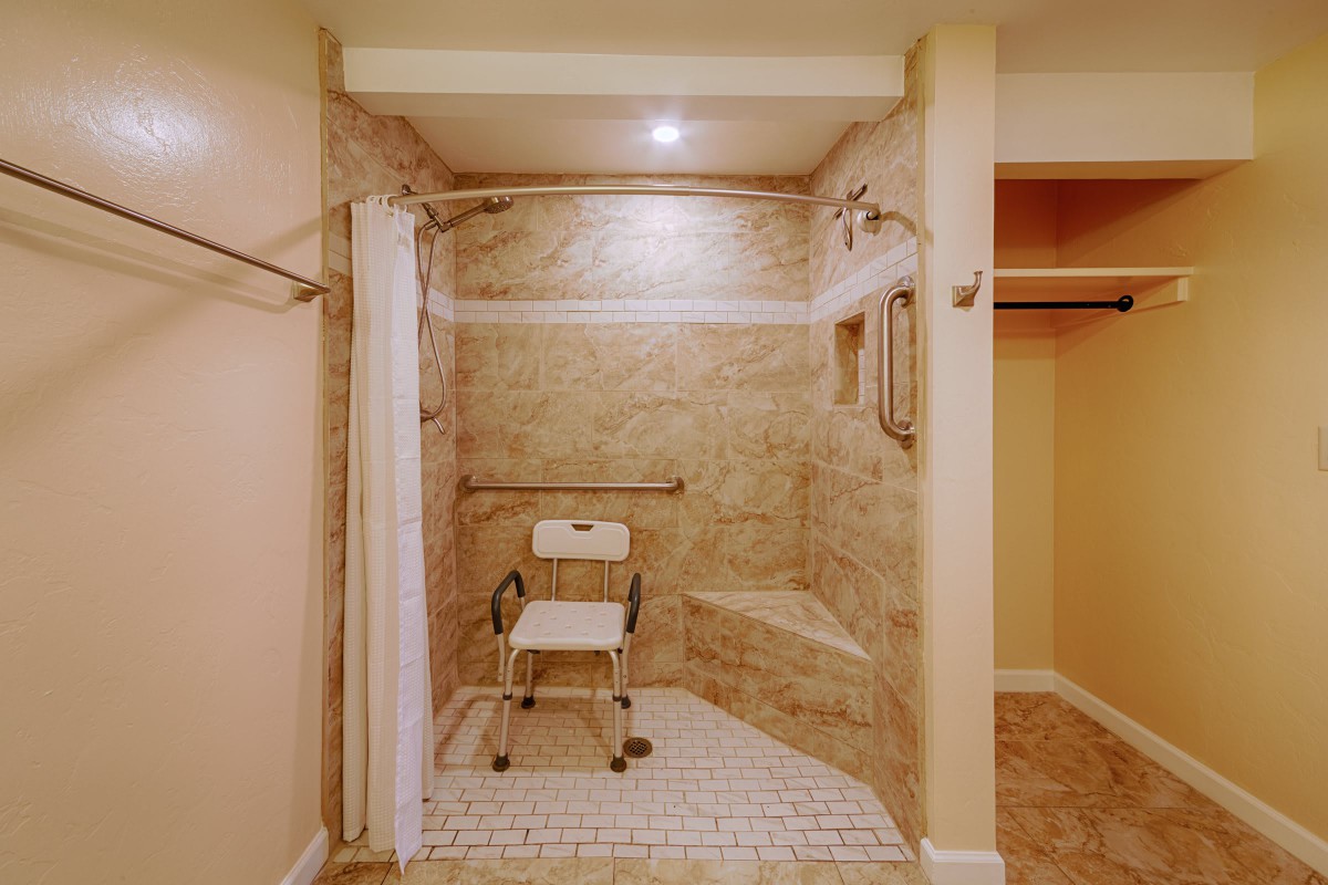 An accessible walk-in shower with a shower chair and safety handrails.