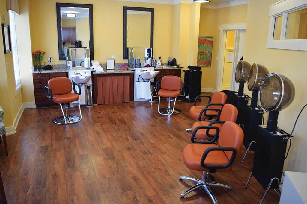 An interior view of a hair salon with several orange chairs and large mirrors.