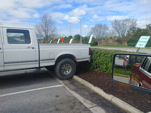 A white truck parked awkwardly, partially on the bushes.