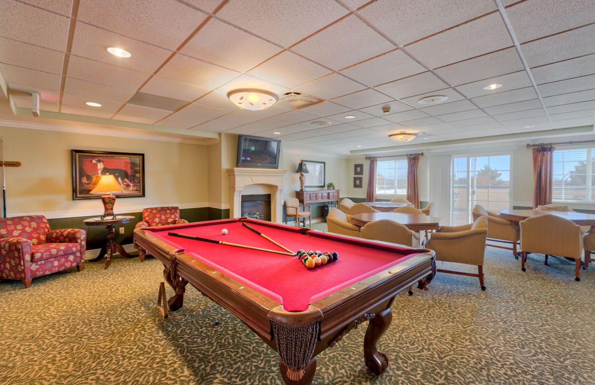 A cozy game room featuring a red pool table and comfortable seating.