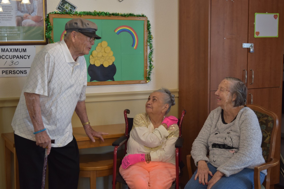 A group of elderly individuals engaging in conversation inside a community setting.