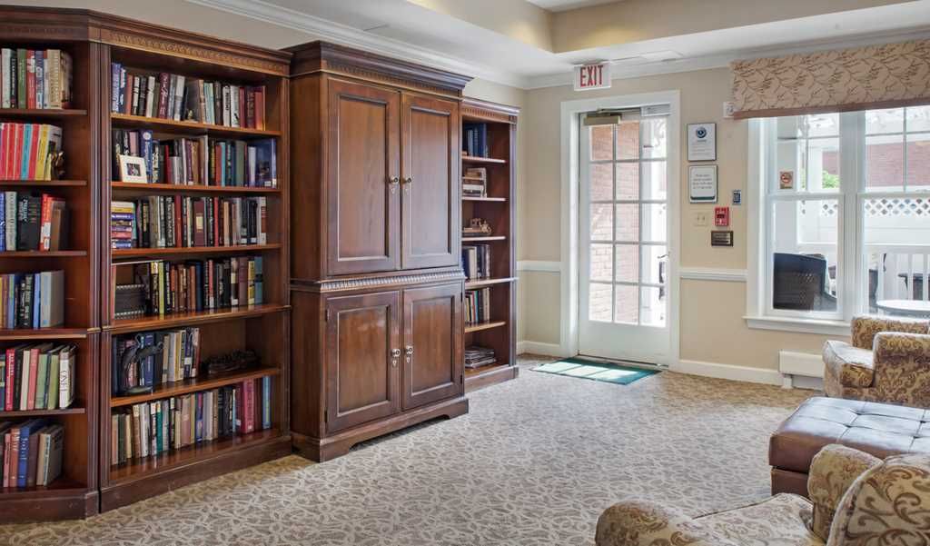 A cozy library corner with wooden bookshelves and a carpeted floor.