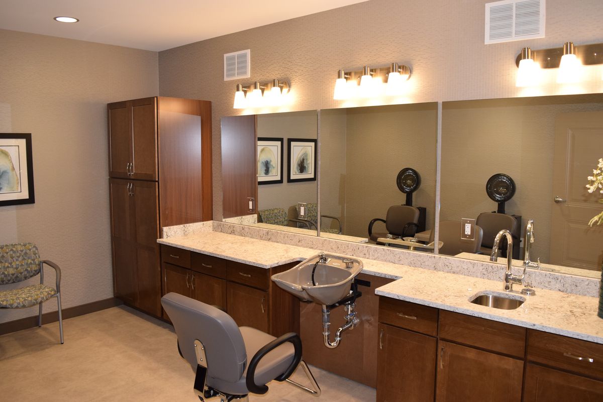 A modern beauty salon interior with chairs, mirrors, and countertops.