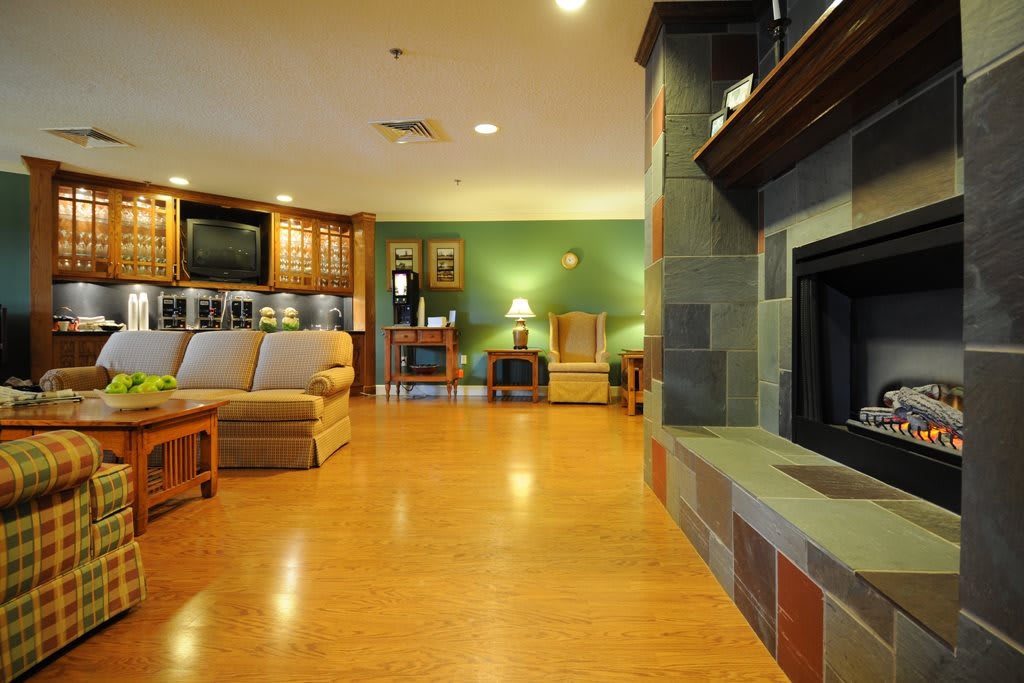 A spacious living room with modern furniture, featuring a cozy fireplace and wooden flooring.