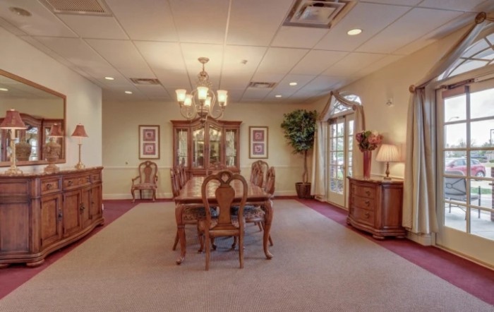 A spacious dining room featuring elegant wooden furniture and a classic chandelier.
