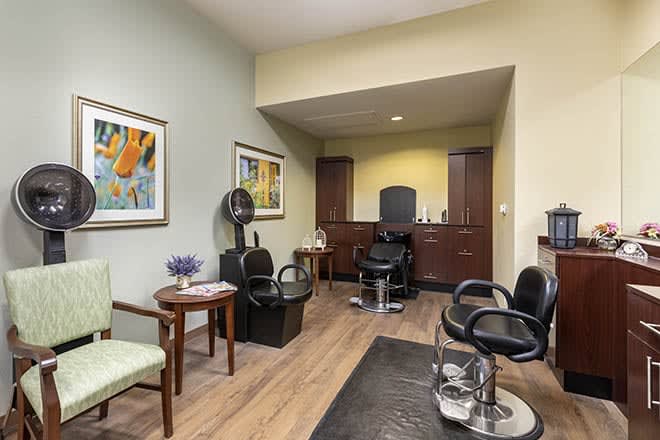 A cozy hair salon interior featuring styling stations, chairs, and decorative paintings.