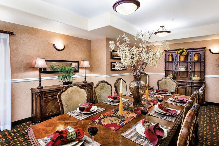 An elegantly set dining table in a warmly lit dining room, featuring decorative floral arrangements and classic furnishings.