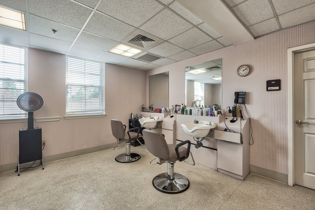 Interior of a salon with two styling chairs and a large mirror.