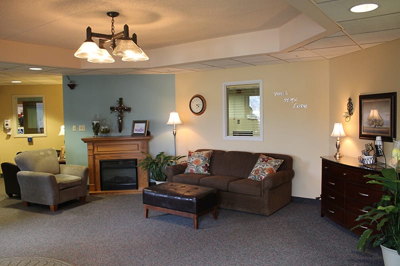 A cozy living room featuring a sectional couch, a fireplace, and warm lighting.