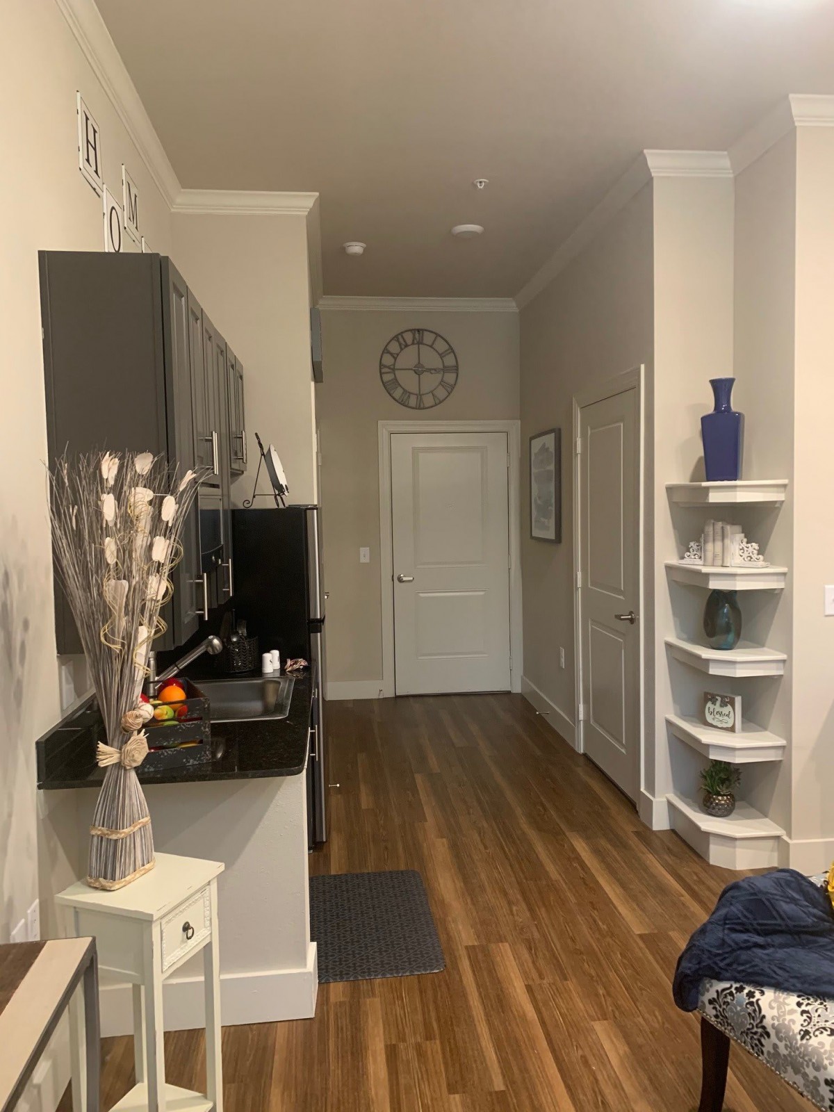 A cozy modern kitchen entrance with wooden flooring and decorative shelving.