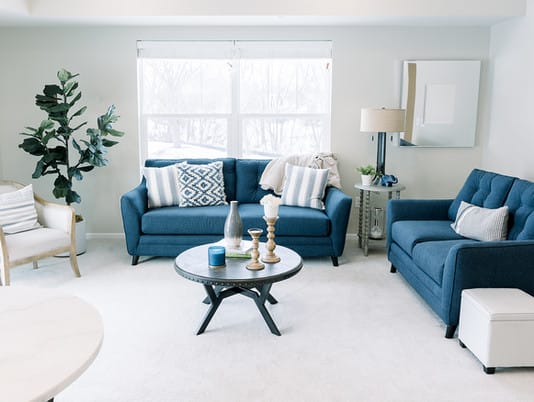 A modern living room featuring blue couches, a stylish coffee table, and decorative accents.