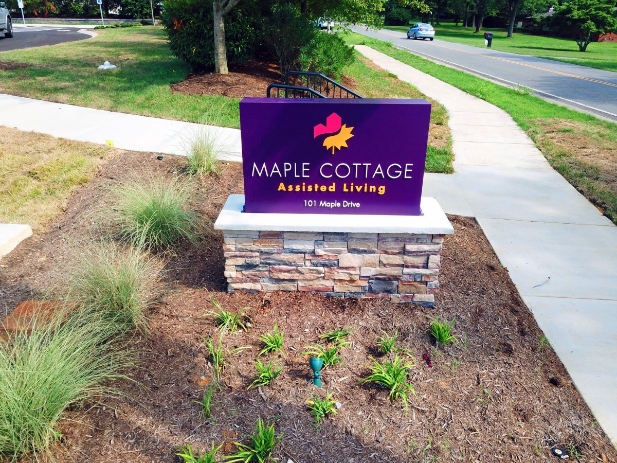 Entrance sign for Maple Cottage Assisted Living surrounded by landscaping.