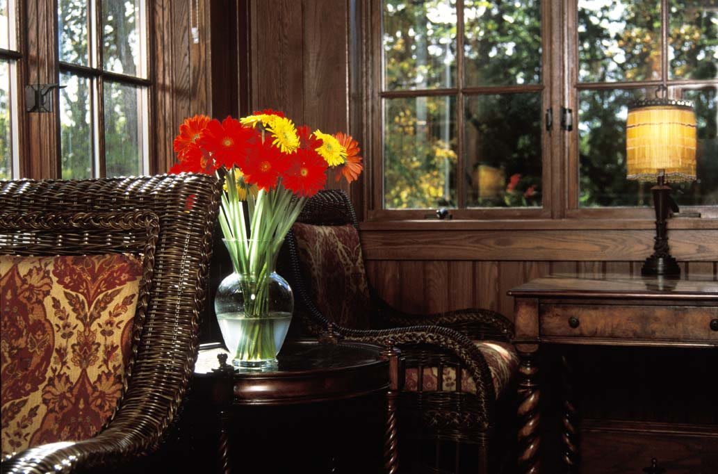 A cozy room with bright flowers in a vase by the window.