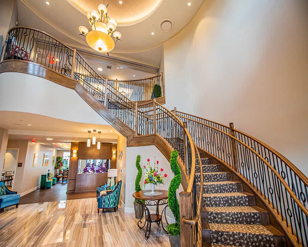 Elegant lobby with a grand staircase and chandelier.