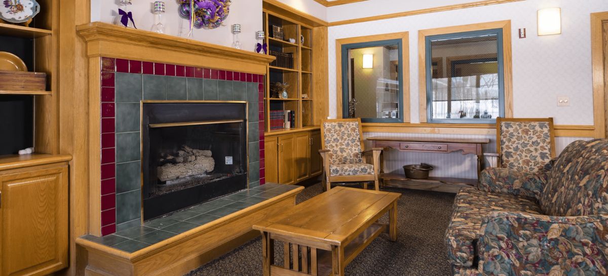 A cozy living room with a fireplace, wooden furniture, and built-in shelves.