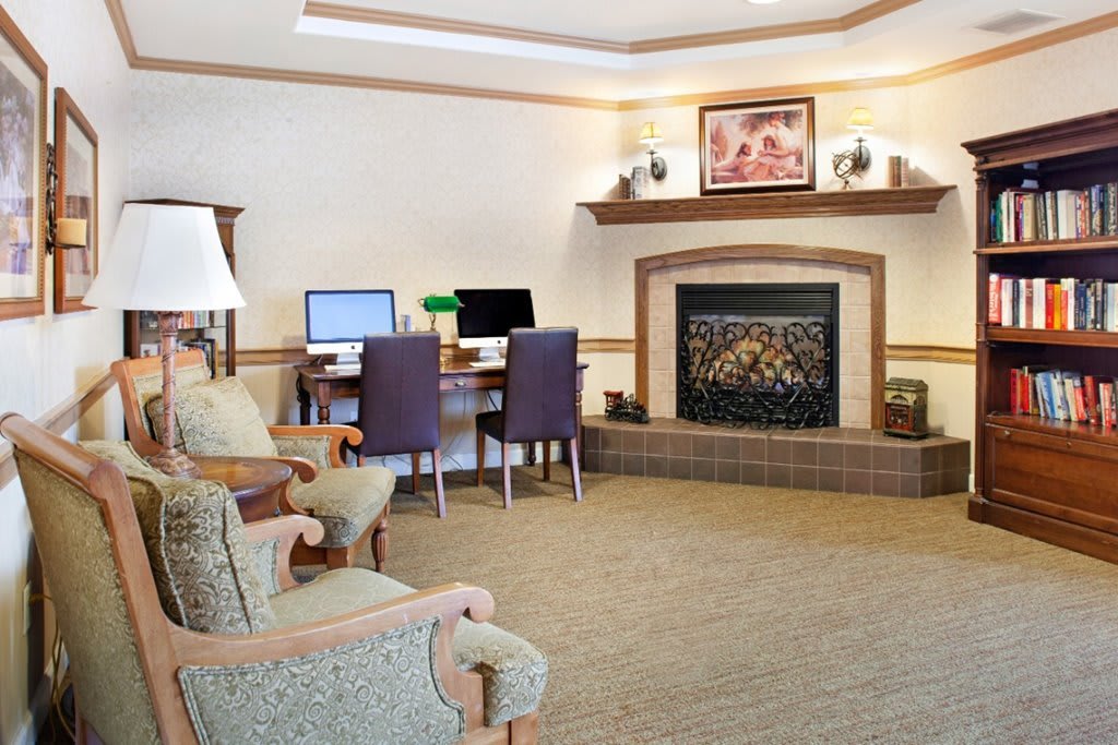 A cozy living room featuring a fireplace and an office area with computers.