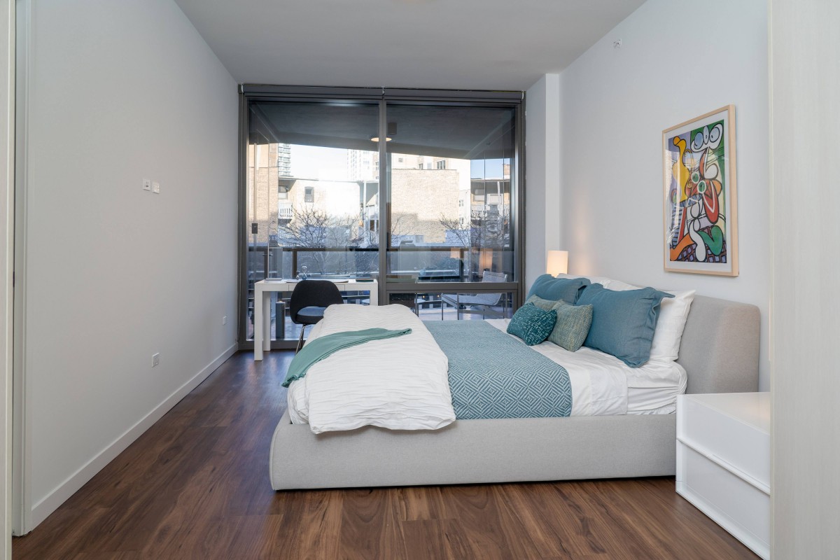 A modern, minimalist bedroom with a comfortable bed, stylish decor, and a view through large windows.