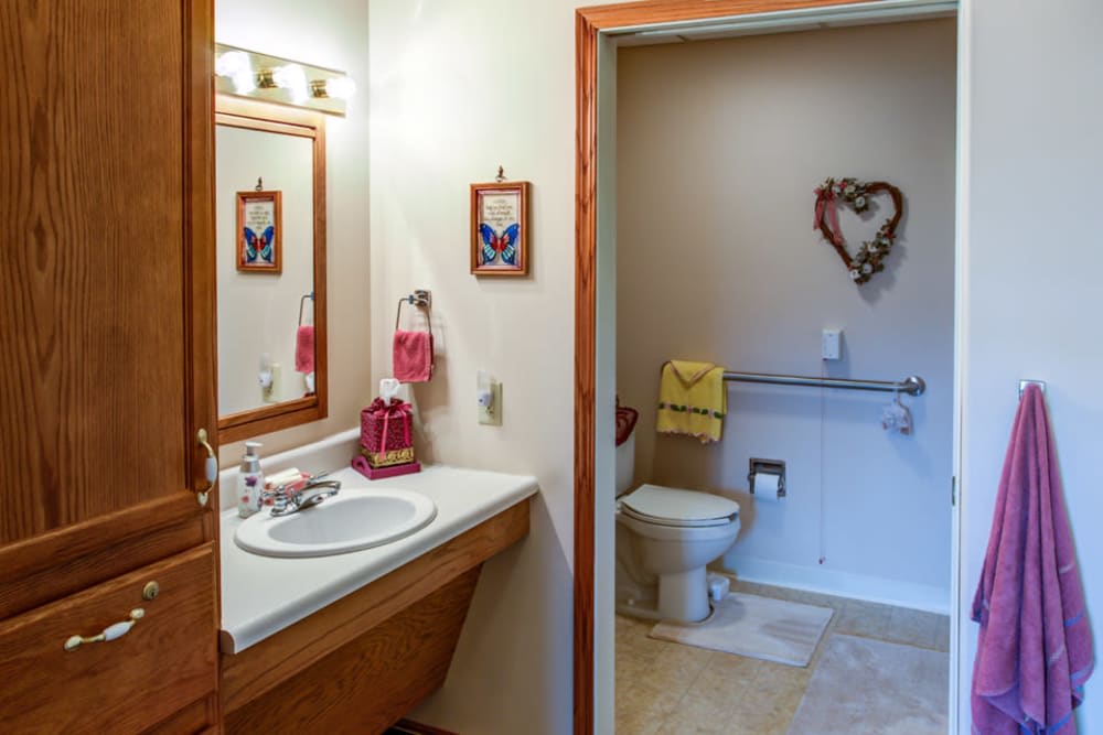 A cozy bathroom with a sink and mirror, decorated with floral wall art and towels.