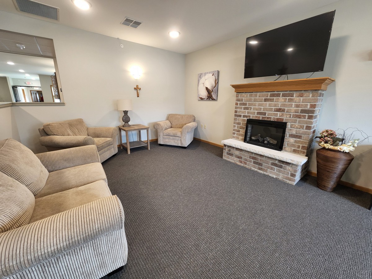 A cozy living room featuring a brick fireplace, comfortable seating, and a mounted TV.