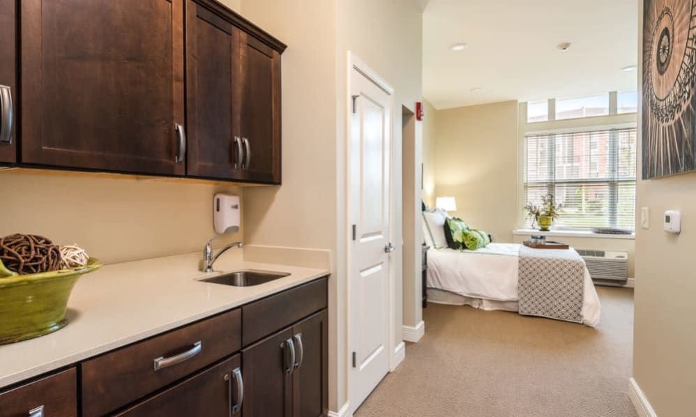 A cozy modern interior with a kitchenette leading into a bright bedroom.