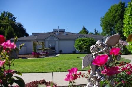 A house with a well-maintained lawn and vibrant flowers in the garden, featuring a small statue.