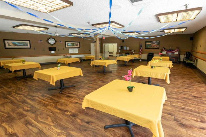 A decorated dining room with yellow tablecloths and wooden flooring.
