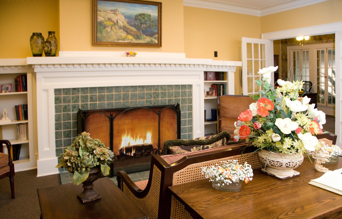 A cozy living room with a fireplace, elegant furniture, and vibrant floral arrangements.