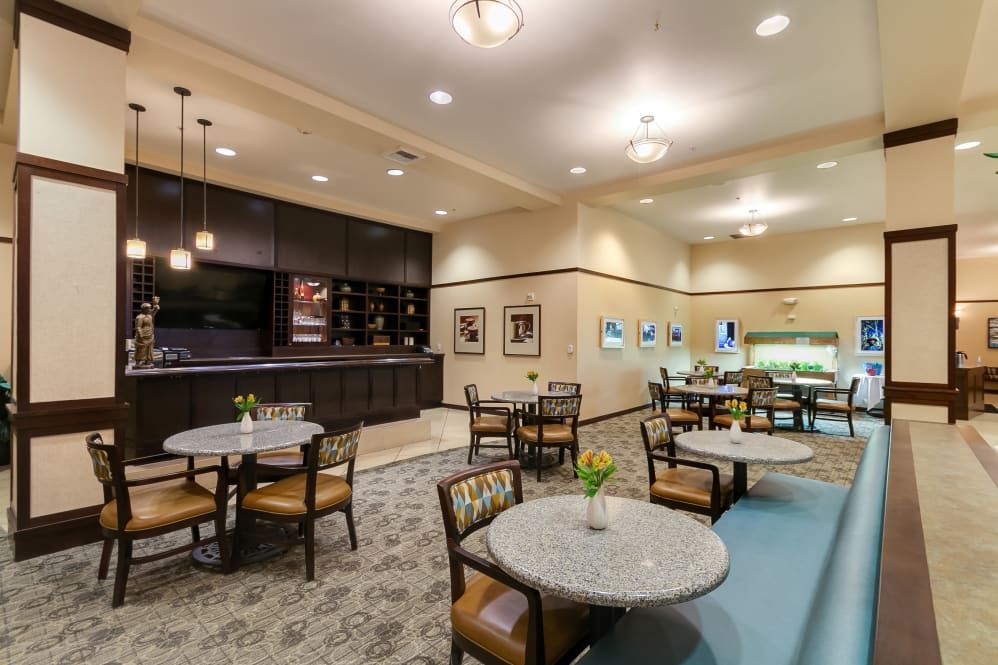 A well-lit dining area with neatly arranged tables and chairs, featuring modern decor and lighting fixtures.