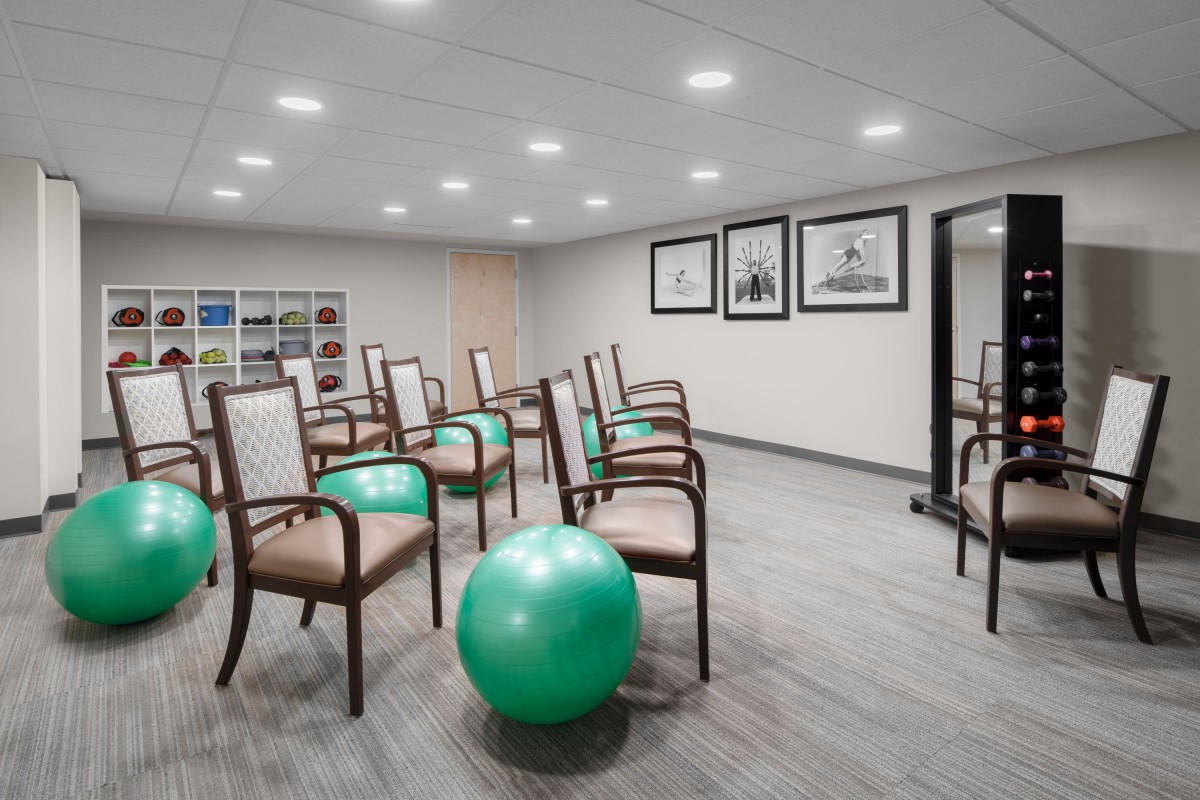 A well-lit exercise room with chairs and fitness balls arranged for a group session.