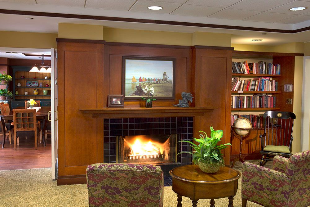 A cozy living room with a fireplace, wood paneling, and a bookshelf, creating a warm and inviting atmosphere.