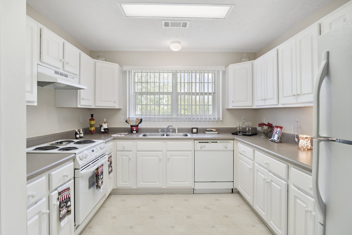 A spacious kitchen with white cabinets and modern appliances.