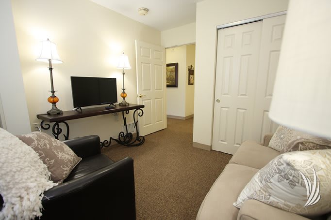 A cozy living room with a sofa, television, and decorative lamps.