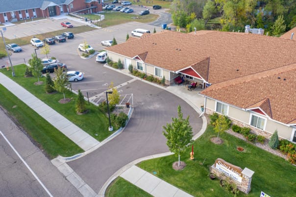Aerial view of a suburban residential building with a parking lot and landscaped surroundings.