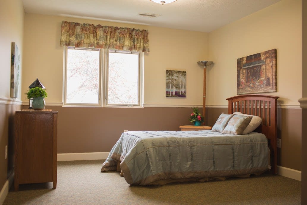 A cozy bedroom with a neatly made bed and natural light coming through the window.