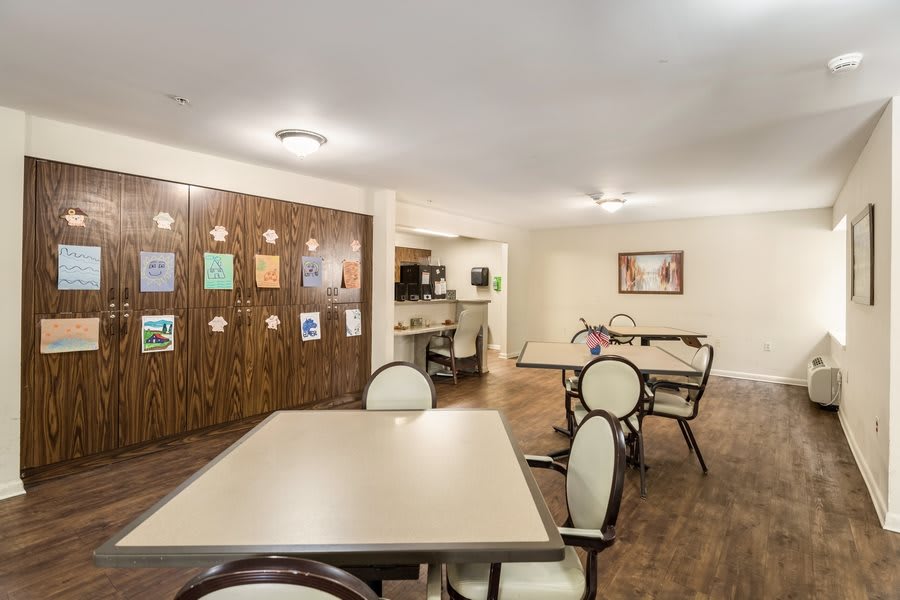 A well-lit dining area with tables and chairs arranged neatly on a wooden floor.