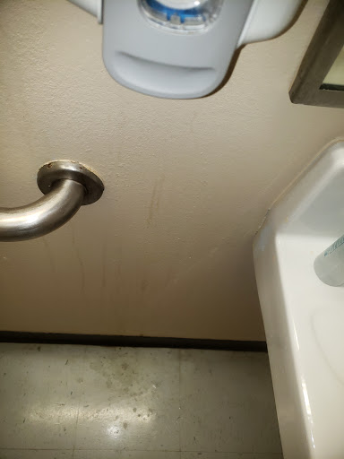 A view of a bathroom sink with a metal railing and wall.