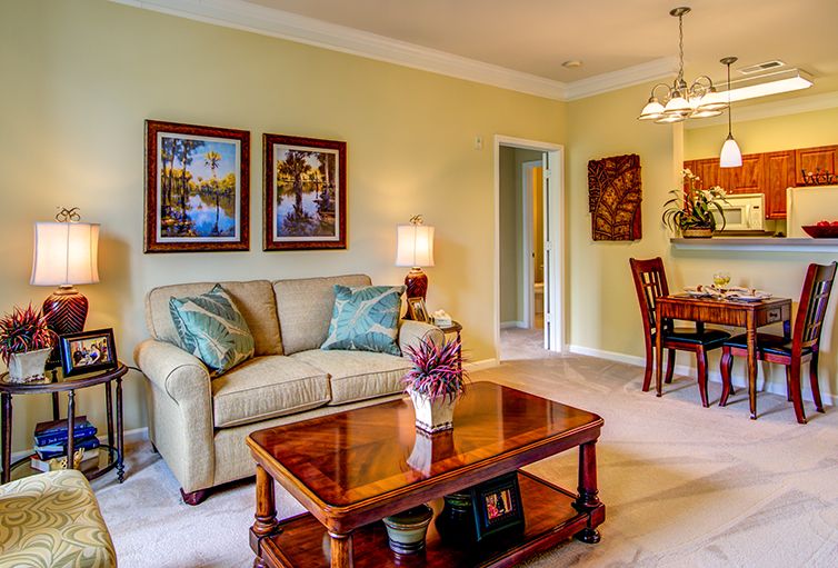 A cozy living room with a comfortable sofa, decorative coffee table, and elegant wall art, leading to a dining area.