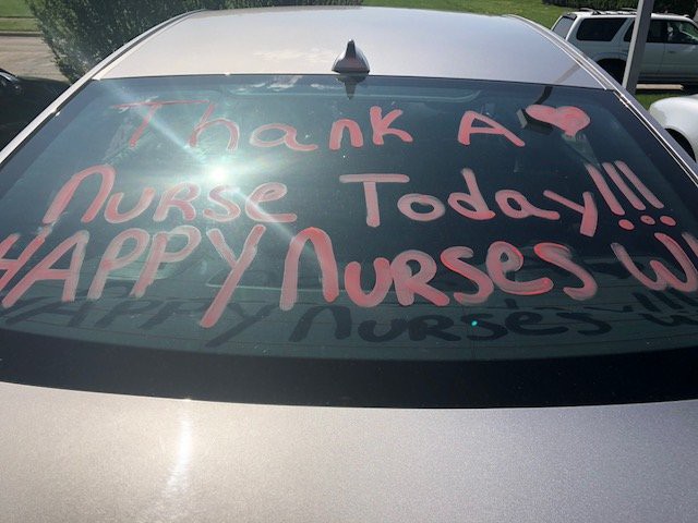 A car window with a message thanking nurses, written in pink letters.