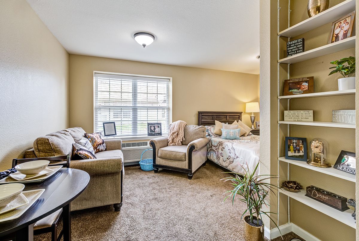 A cozy living space combining a bedroom and seating area with comfortable furniture and natural light.