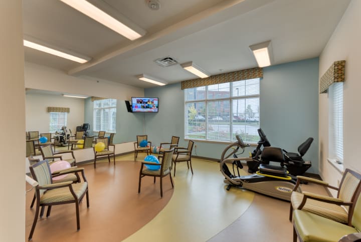 A physical therapy room with exercise equipment and seating.
