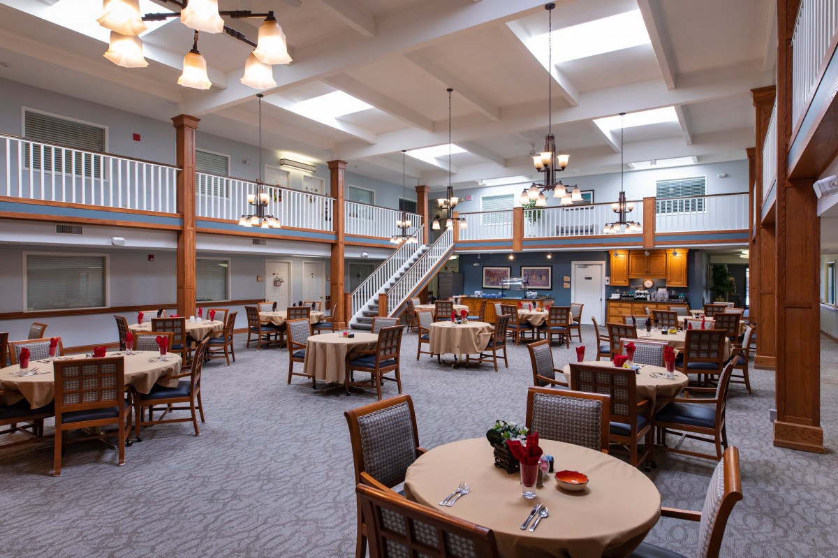 A spacious dining hall with multiple tables, chandeliers, and a modern interior design.
