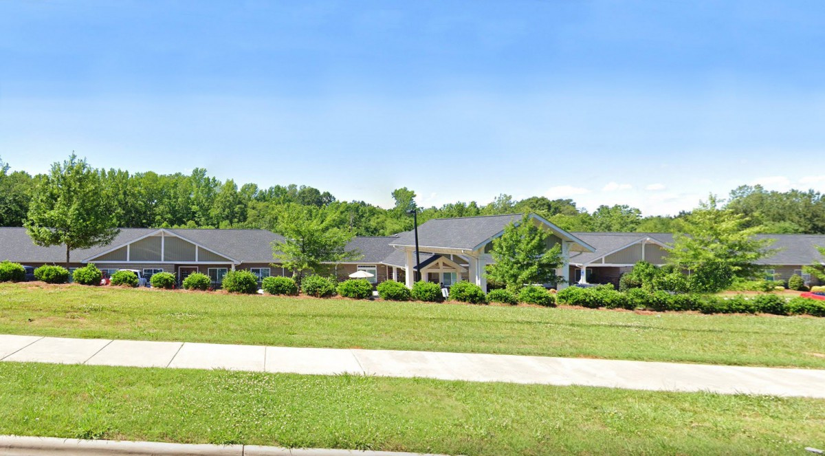 A suburban house with a large front lawn and surrounding trees.