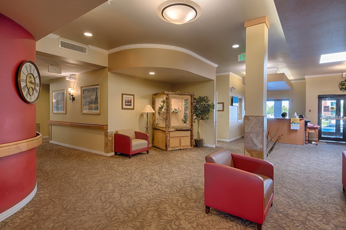 A well-lit lobby with red chairs, a carpeted floor, and decorative elements.