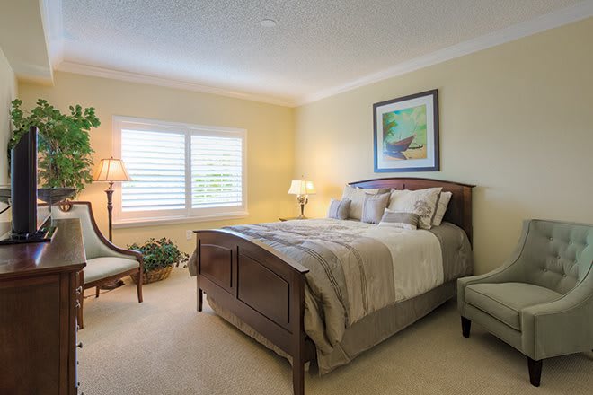 A cozy and well-lit bedroom with a comfortable bed, elegant lamps, and tasteful decor.