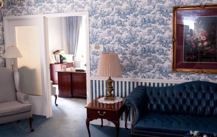 A vintage-themed living room with blue patterned wallpaper and classic furniture.