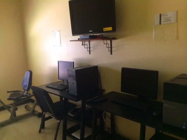 A small office space with two computer workstations and a wall-mounted television.